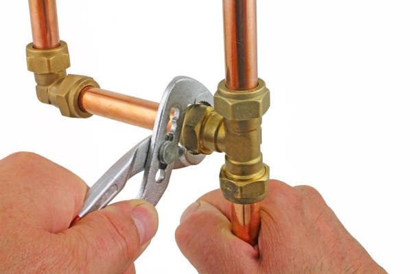 Two adjustable wrenches remove compression fitting from copper pipework